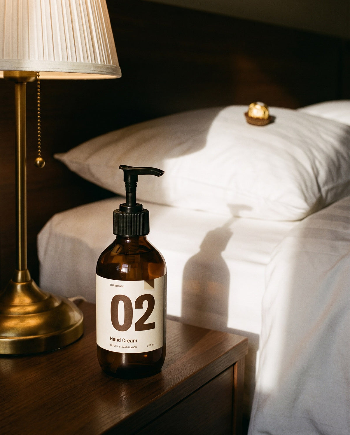No. 02 on a bedside table next to a turned-down hotel bed
